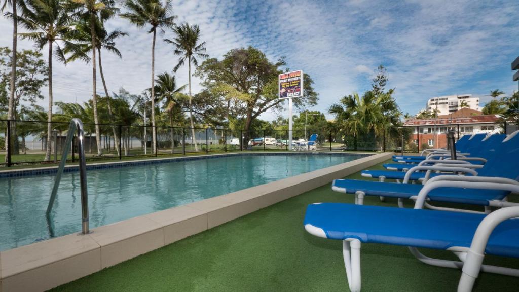 凯恩斯珊瑚塔假日酒店的一个带蓝色椅子的游泳池,棕榈树