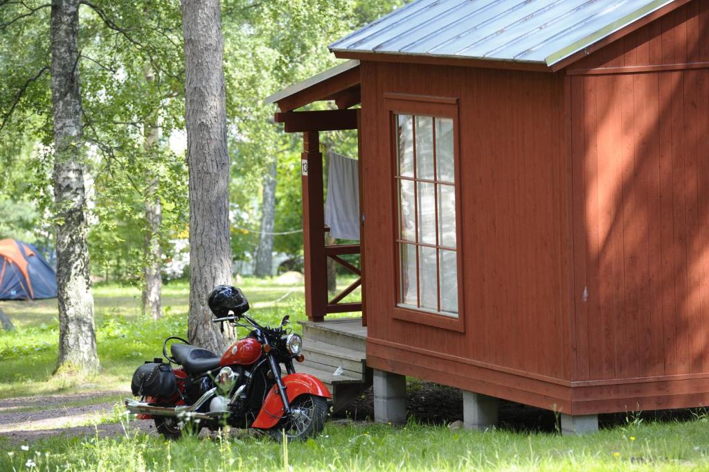 玛丽港格隆纳乌登斯露营酒店的停在小房子前面的一辆红色摩托车