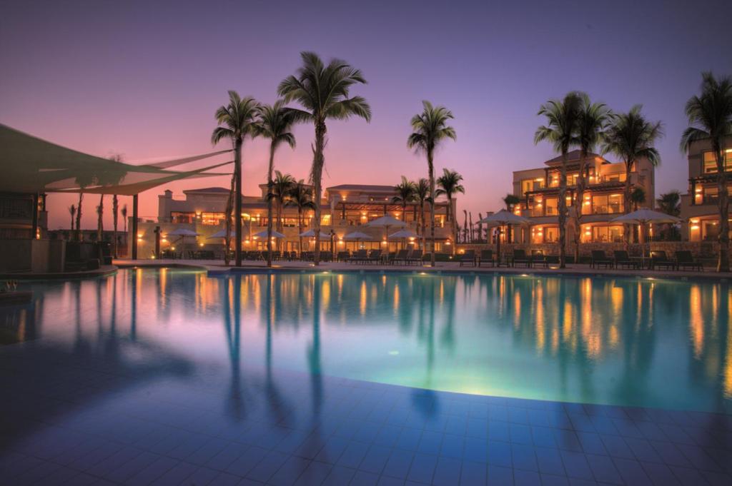 艾因苏赫纳小威尼斯高尔夫杰斯酒店&度假村的一座棕榈树酒店游泳池和一座建筑