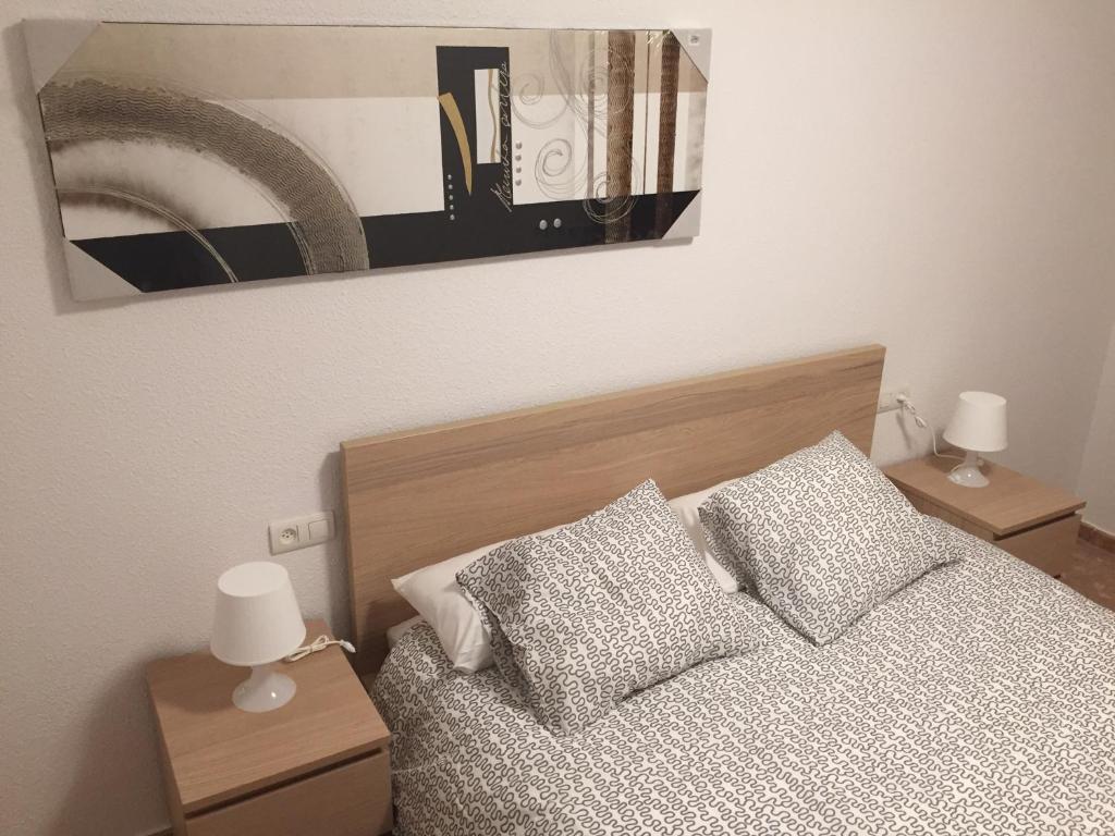 特鲁埃尔Apartamento Torre del Salvador的一张带两个枕头的床和一张墙上的照片