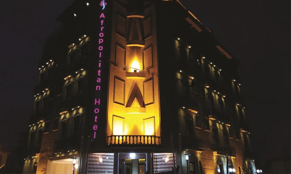 亚的斯亚贝巴Afropolitan Hotel的一座建筑物,晚上在建筑物的一侧有标志