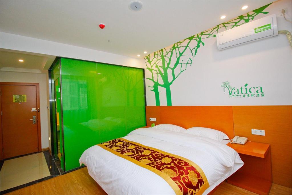 肃州格林豪泰酒店集团青皮树酒泉西汉胜迹盛世酒店的一间卧室配有一张带绿色墙壁的床