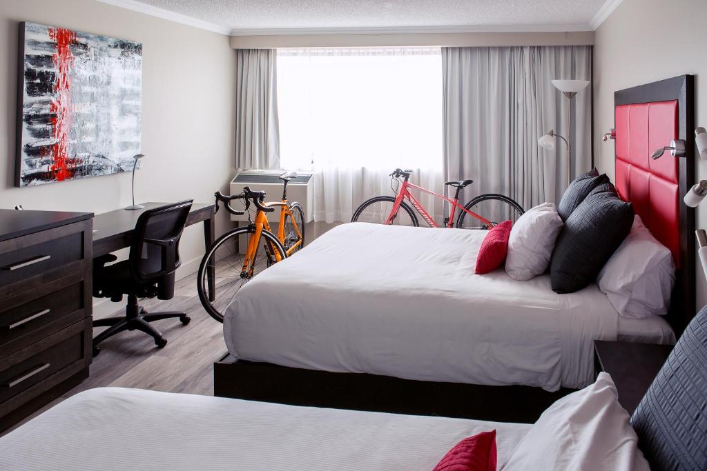 阿尔马Hotel Universel Alma的酒店客房带两张床、书桌以及自行车