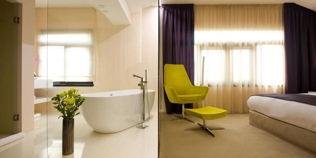 萨图马雷Hotel Vila Class的带浴缸、床和黄色椅子的浴室