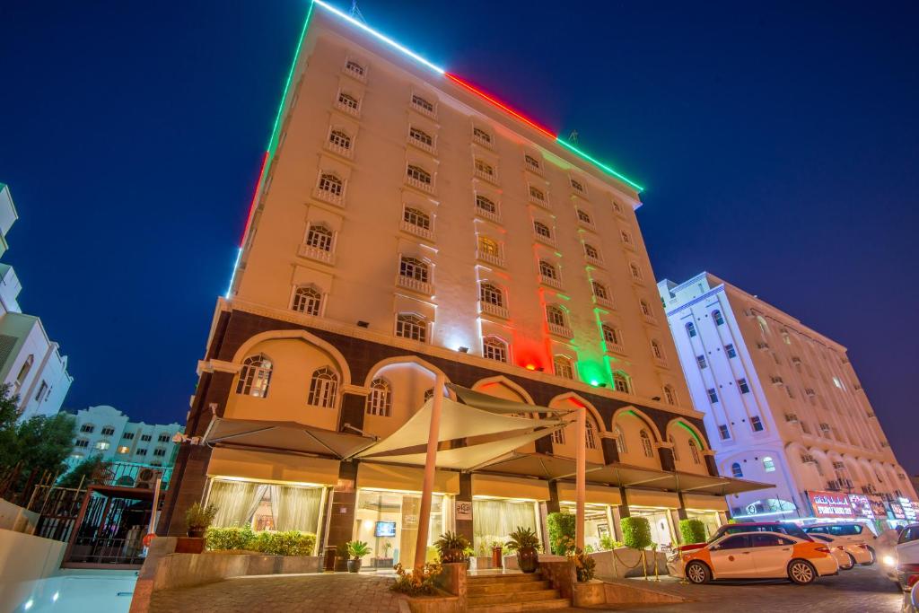马斯喀特Caesar Hotel的一座酒店建筑,上面有绿色和红色的灯光