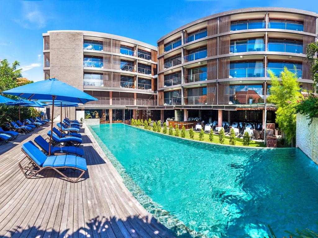 金巴兰巴厘岛沃特马克Spa酒店的酒店设有带椅子和遮阳伞的游泳池