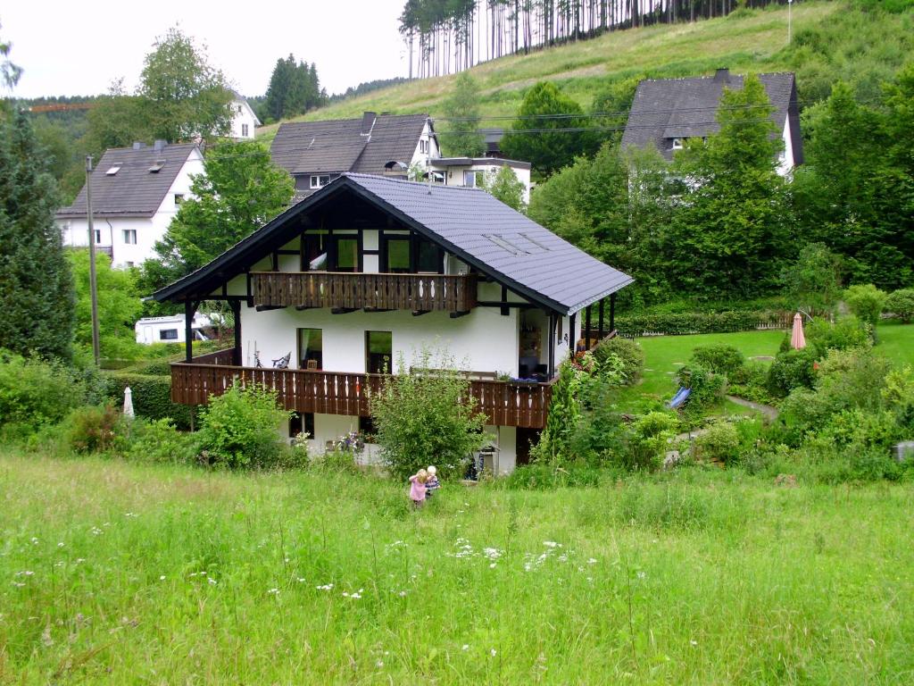 施马伦贝格Ferienwohnung Schmallenberg的山坡上的房子,一个女孩站在田野里