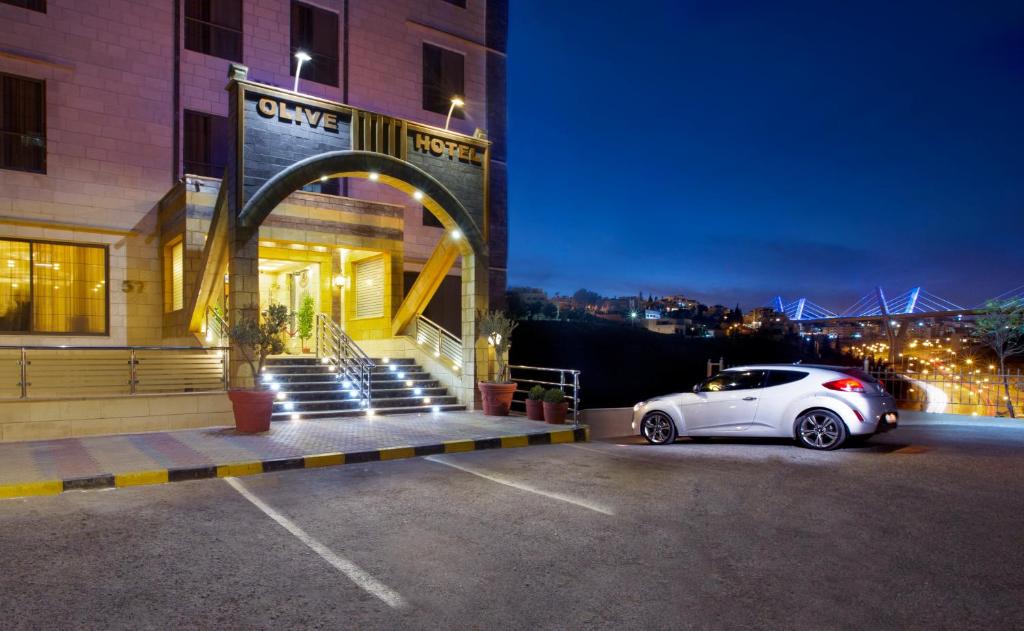 安曼Olive Hotel Amman的停在大楼前停车场的白色汽车