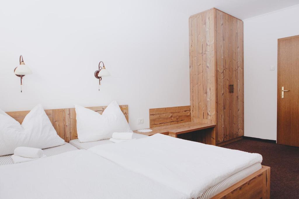 PrevaljeGostišče Krivograd的卧室配有白色的床和木制橱柜。