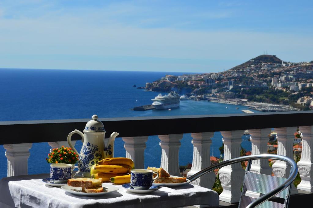 丰沙尔Charming Apartments in Funchal - São Gonçalo的阳台上的餐桌和食物,享有海景