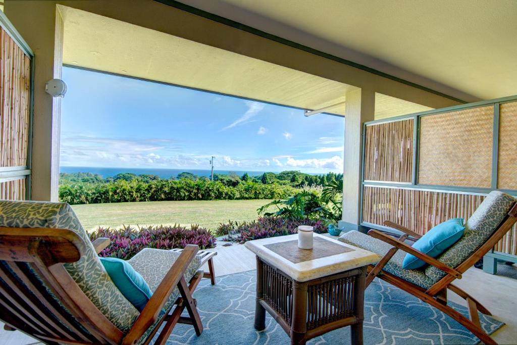 North Hilo马哈娜之家乡村宾馆的门廊配有椅子和桌子,并设有大窗户
