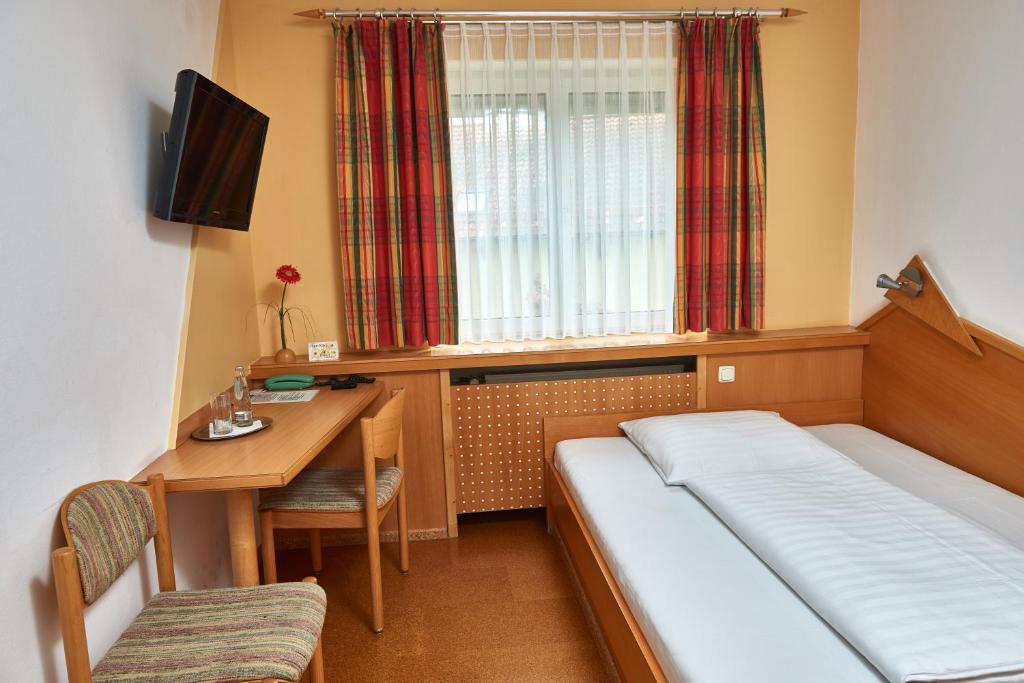 Obertraubling加斯霍夫沙特科尔酒店的一间卧室配有一张床、一张书桌和一个窗户。