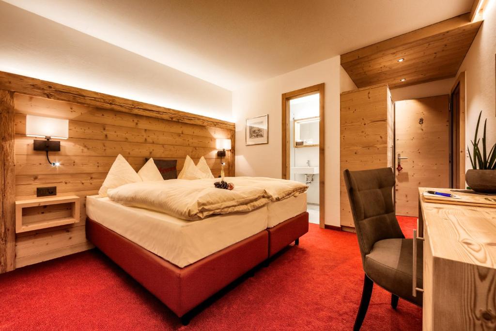 阿罗萨阿罗萨阿尔卑斯酒店的一间卧室配有一张大床和一把椅子