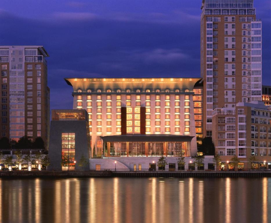 伦敦加那利滨江广场酒店的一座大建筑,上面有灯,旁边是水体