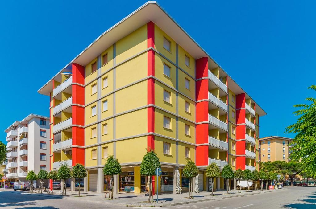 比比翁Apartments in Bibione 25584的街上的一座黄色和红色的建筑