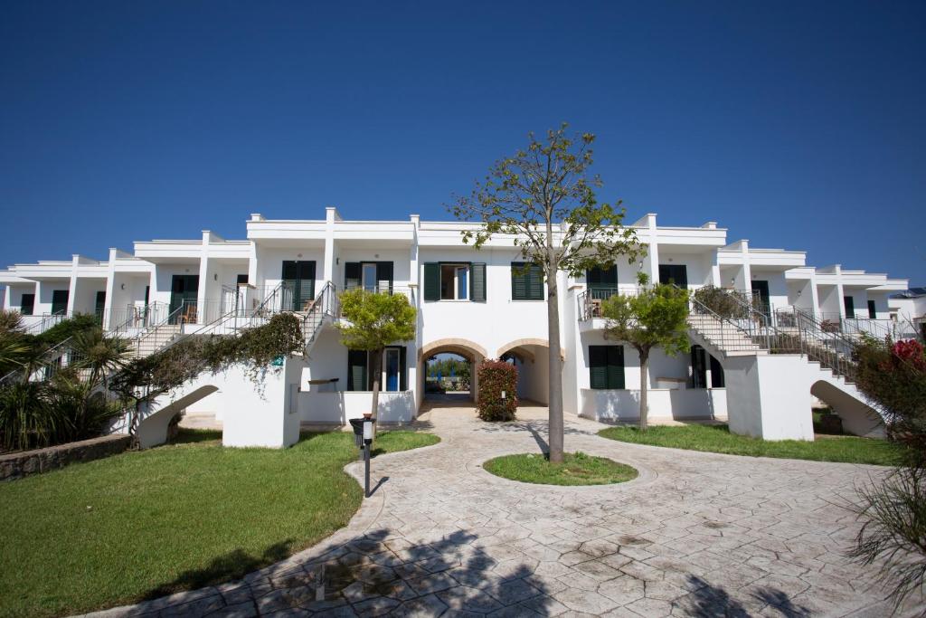 圣伊西多罗塞娃吉奥港度假酒店的一座白色的大建筑,有楼梯和草地
