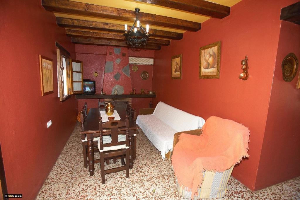 埃尔博斯克Casa del Huerto的客厅设有红色的墙壁、一张沙发和一张桌子