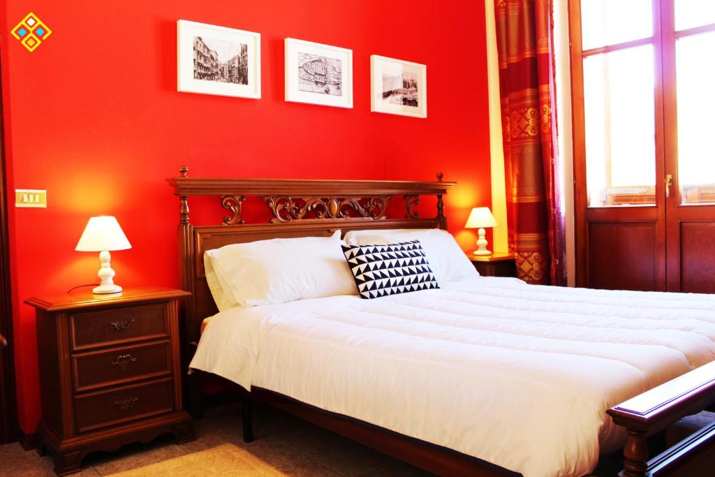 卡利亚里Torre dello Sperone的红色卧室设有一张大床和两盏灯。