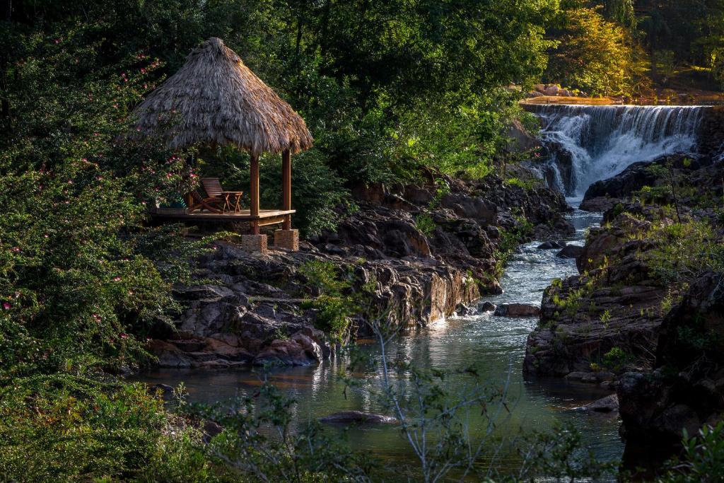 圣伊格纳西奥布兰克尼奥克斯山林小屋的一条河旁的瀑布,有长凳和小屋
