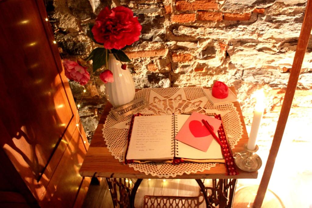 科莫勒达米德拉科尔塞拉住宿加早餐旅馆的一张桌子,上面有一本书,还有一朵玫瑰花花花瓶