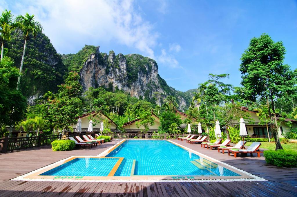 奥南海滩Aonang Phu Petra Resort, Krabi - SHA Plus的一座带椅子的度假游泳池,一座山底