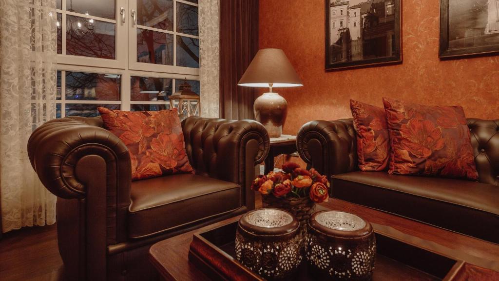 克拉科夫Main Street Apartments的客厅配有两张真皮座椅和一张桌子