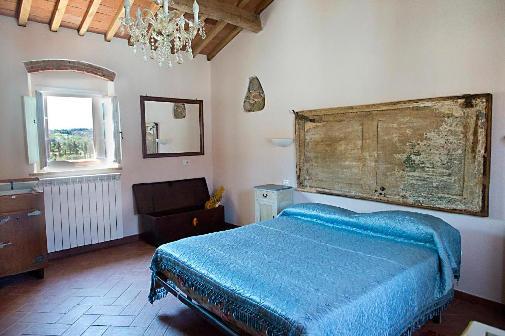 CrespinaAgriturismo L'isola的一间卧室设有一张床、一个窗户和一个吊灯。