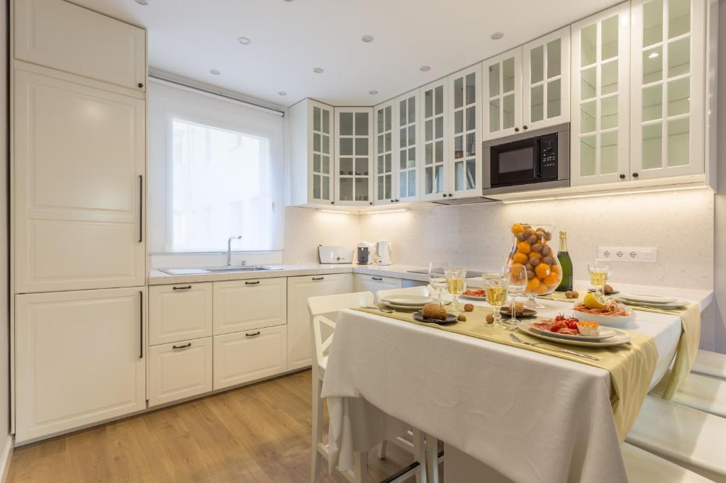 巴塞罗那莫利亚多公寓的厨房配有白色橱柜和一张带食物的桌子。