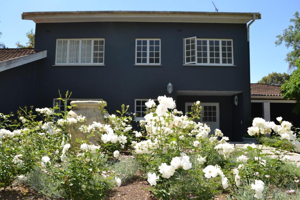 惠灵顿The Garden Shed Guest House的前面有白色花的黑色房子