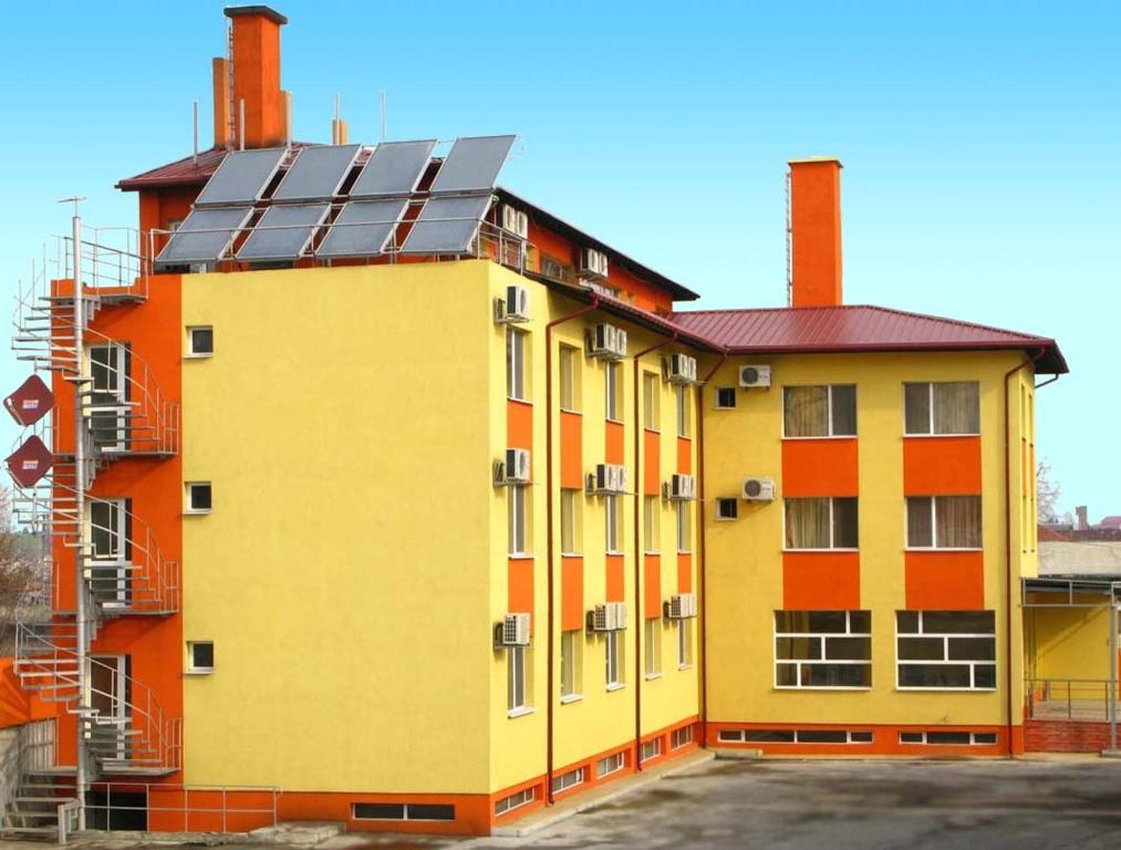 Radnevo纳克拉酒店的一座黄色和橙色的建筑,上面有太阳能电池板