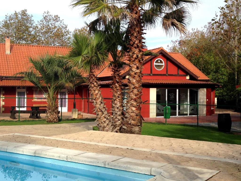 伊诺赫多Hostel albergue Paradiso的一座棕榈树红色的房子和一个游泳池