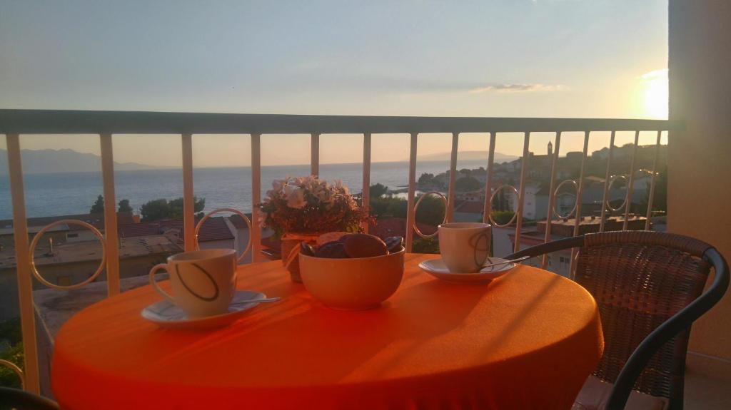 格拉达茨Apartments Roncevic #JOKO#的阳台上的桌子上放有杯子和碟子