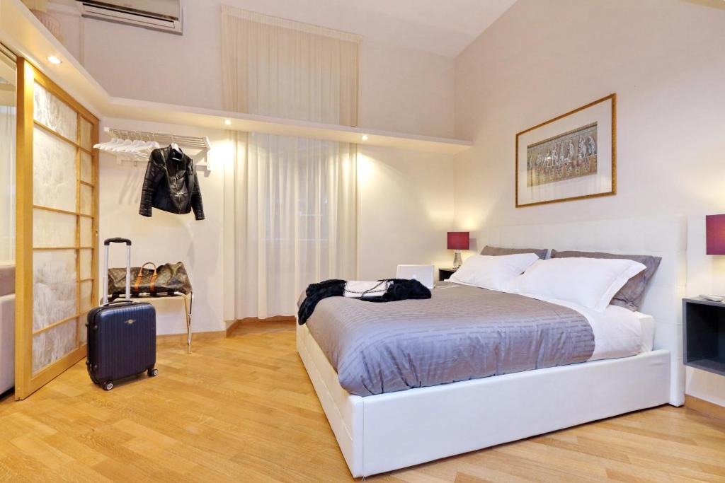 罗马VENETO COMFORTABLE Apartment的一间白色卧室,配有一张床和一个行李箱