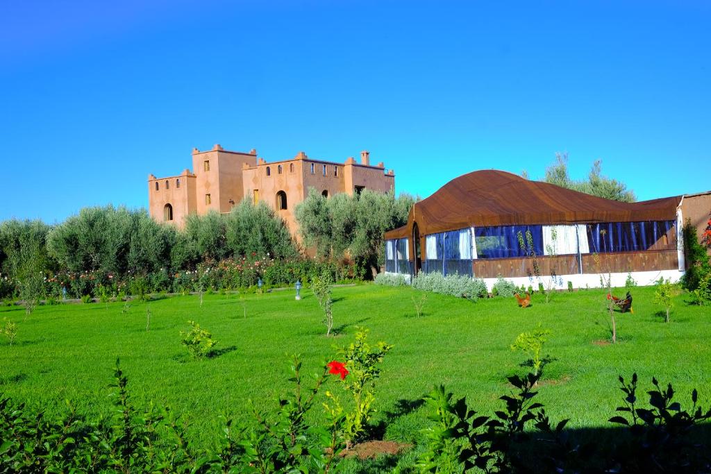 马拉喀什Ferme Sidi Safou & Spa的绿色的田野,有建筑和城堡