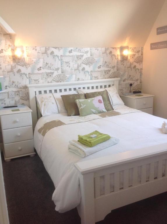 大雅茅斯克里斯伍德贵宾酒店的卧室配有一张大白色床,墙上挂着鲜花