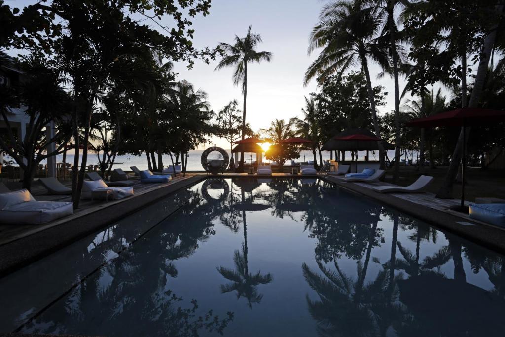 隆卡比劳圣殿海滩潜水度假村的棕榈树和日落度假村的游泳池