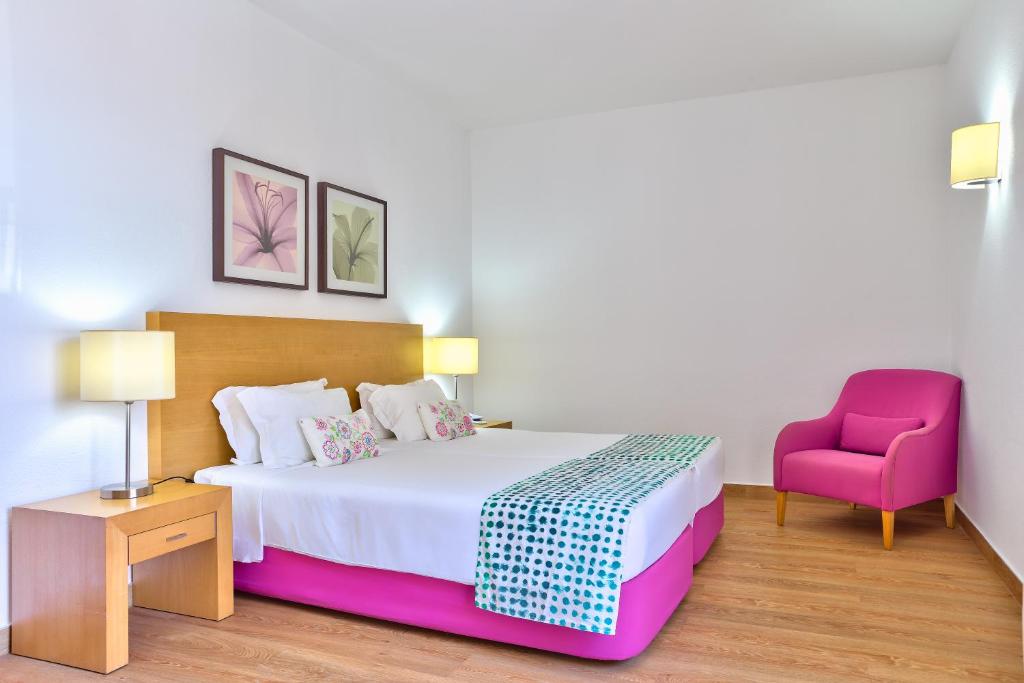 圣港托雷普拉亚酒店的一间卧室配有一张床和一张粉红色的椅子
