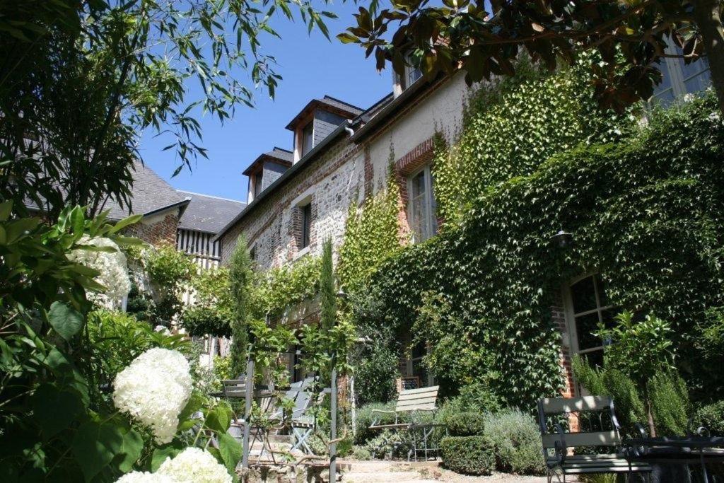 翁弗勒尔La Cour Sainte Catherine demeure de charme的花园内带长椅和藤蔓覆盖的建筑