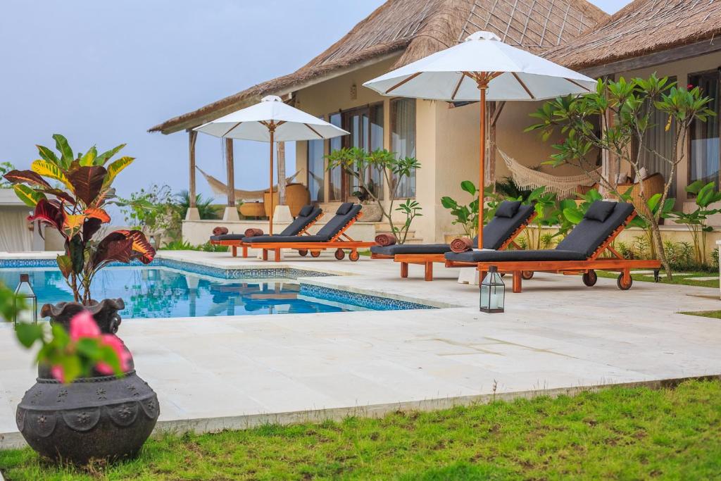 乌鲁瓦图曼陀罗村阳光屋度假村的一个带躺椅和遮阳伞的度假游泳池