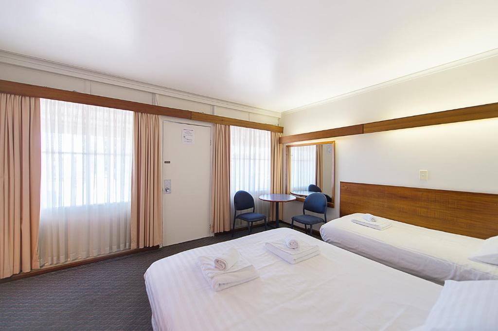 霍巴特蓝山汽车旅馆的酒店客房带两张床和一张桌子以及椅子。