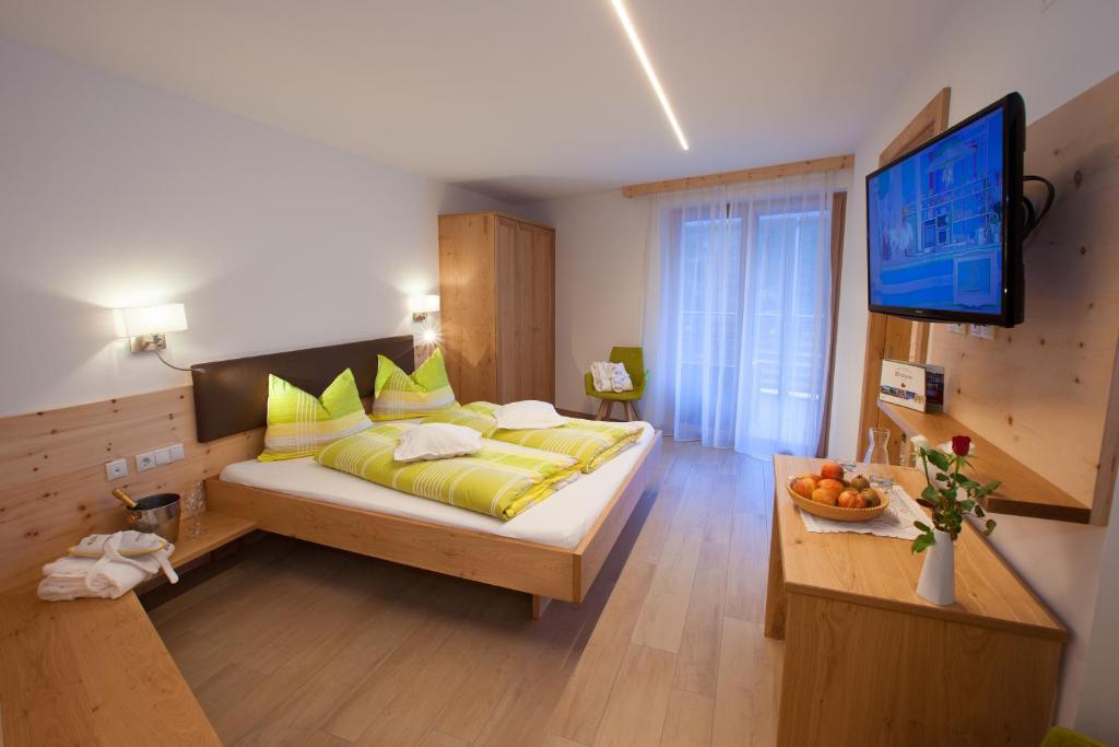 马尔泰洛Hotel Restaurant Waldheim的一间卧室配有一张带黄色枕头的床和电视。