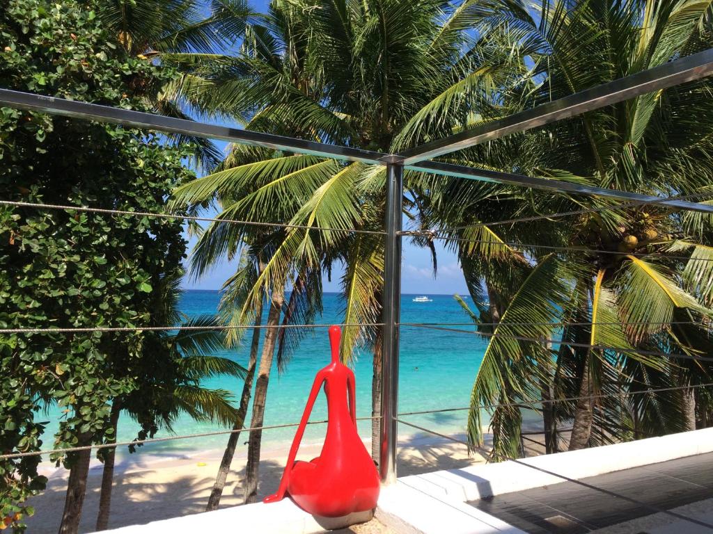 长滩岛日落海滩一室公寓式酒店的红色的花瓶坐在窗户上,眺望着海滩