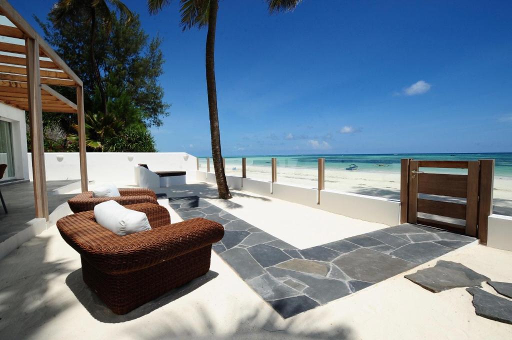 吉汶瓦Amani Home - Moja Private Beach Suite的一个带两把椅子的庭院和海滩