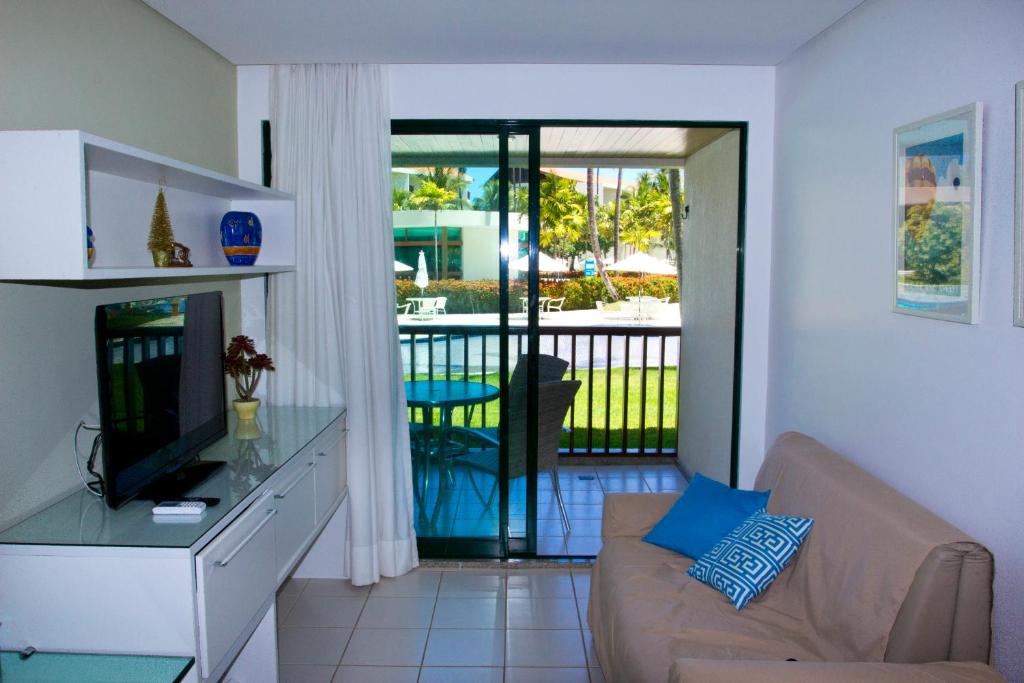 嘎林海斯港FLAT MARULHOS SUÍTES E RESORT的带沙发和电视的客厅以及阳台。
