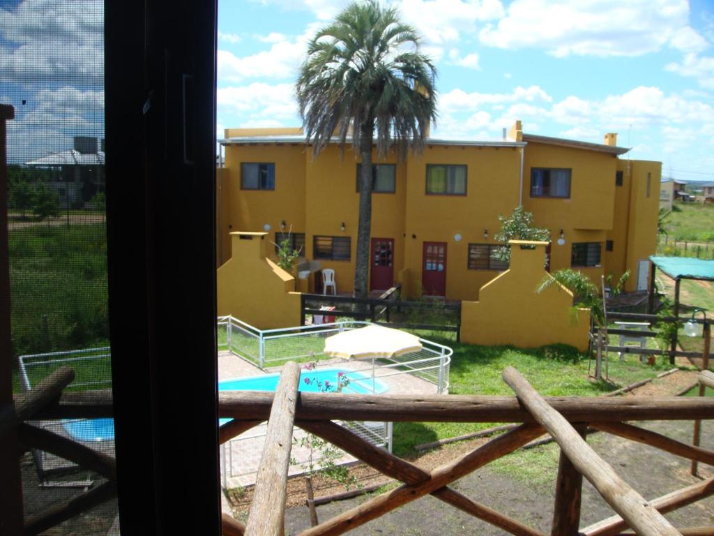 科隆Yataí Casas的棕榈树和游泳池的黄色房子