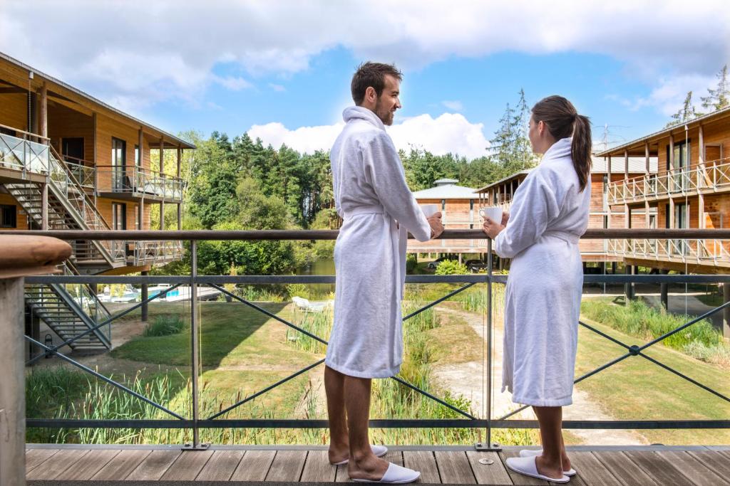 布吕兹Domaine de Cicé-Blossac, Resort Spa & Golf的身着白色长袍的男人和女人站在阳台上