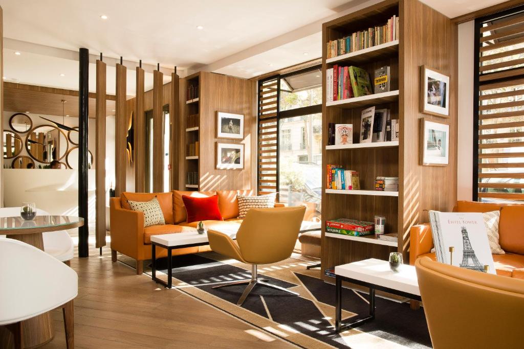 巴黎艾菲尔蒂雷纳酒店的图书馆配有橙色椅子和书架