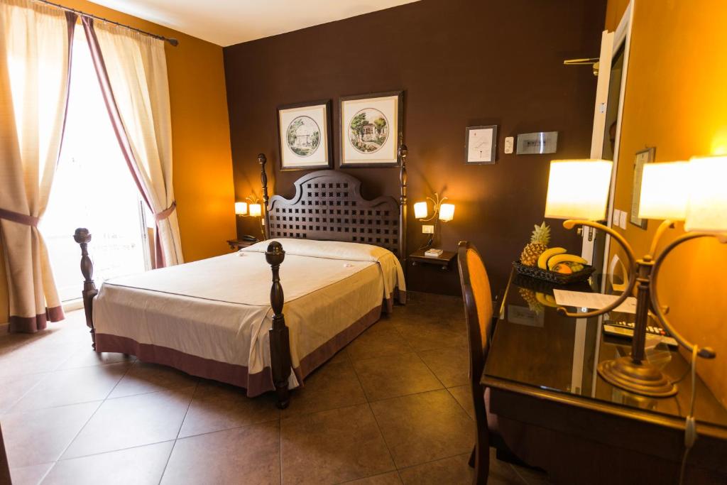锡拉库扎科隆尼阿里酒店的一间卧室配有一张床、一张桌子和一个窗户。