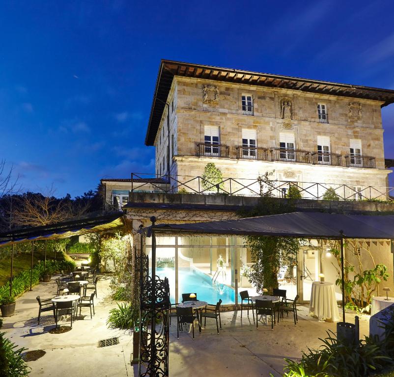 蒙希亚Hotel Palacio Urgoiti的一座配有桌椅的建筑和一个游泳池