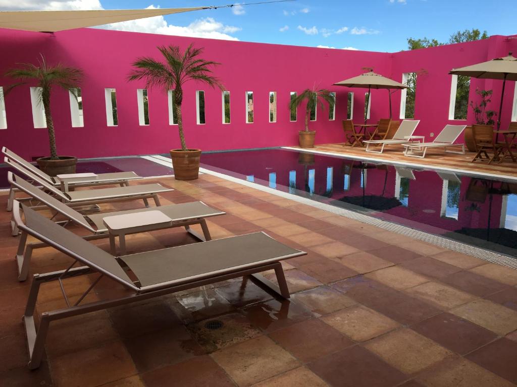 普埃布拉卡萨雷纳精品酒店的一个带躺椅和粉红色墙壁的游泳池